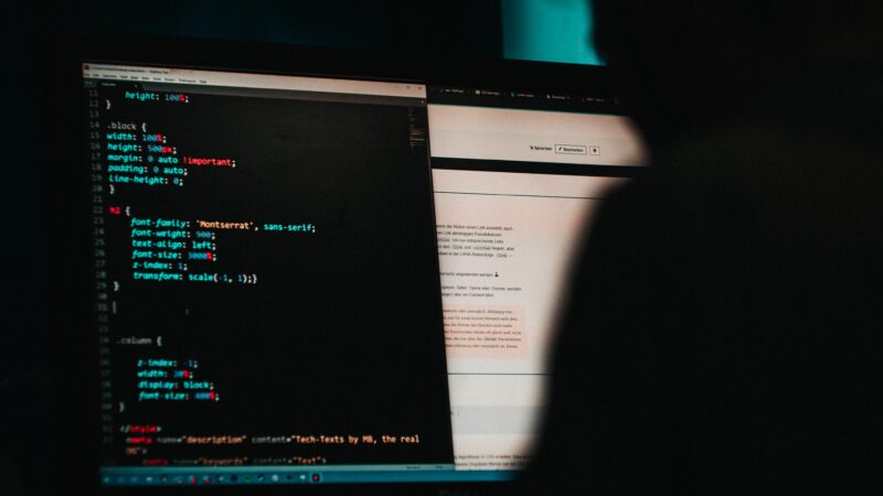 Shadowy figure reading html on dark computer screen