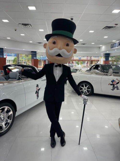 Mr. Monopoly posing with Monopoly cars
